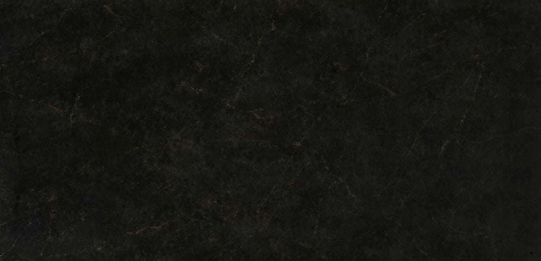 A close-up of a dark textured surface, likely a black stone, tile, or leather material with subtle warm brown veining.